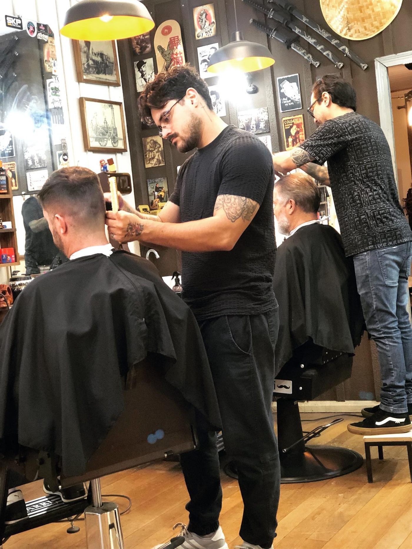 Dois barbeiros da Estação atendendo clientes no salão